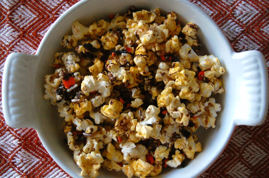 overhead view of bowl with cozy corn popcorn on top of orange, diamond-patterned cloth