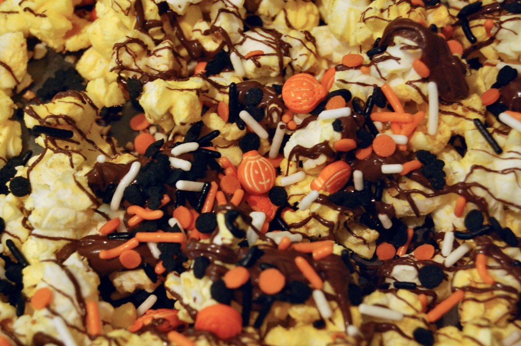 close-up of cozy corn popcorn: buttered popcorn, drizzled chocolate, and sprinkles, centered on a smiling pumpkin sprinkle